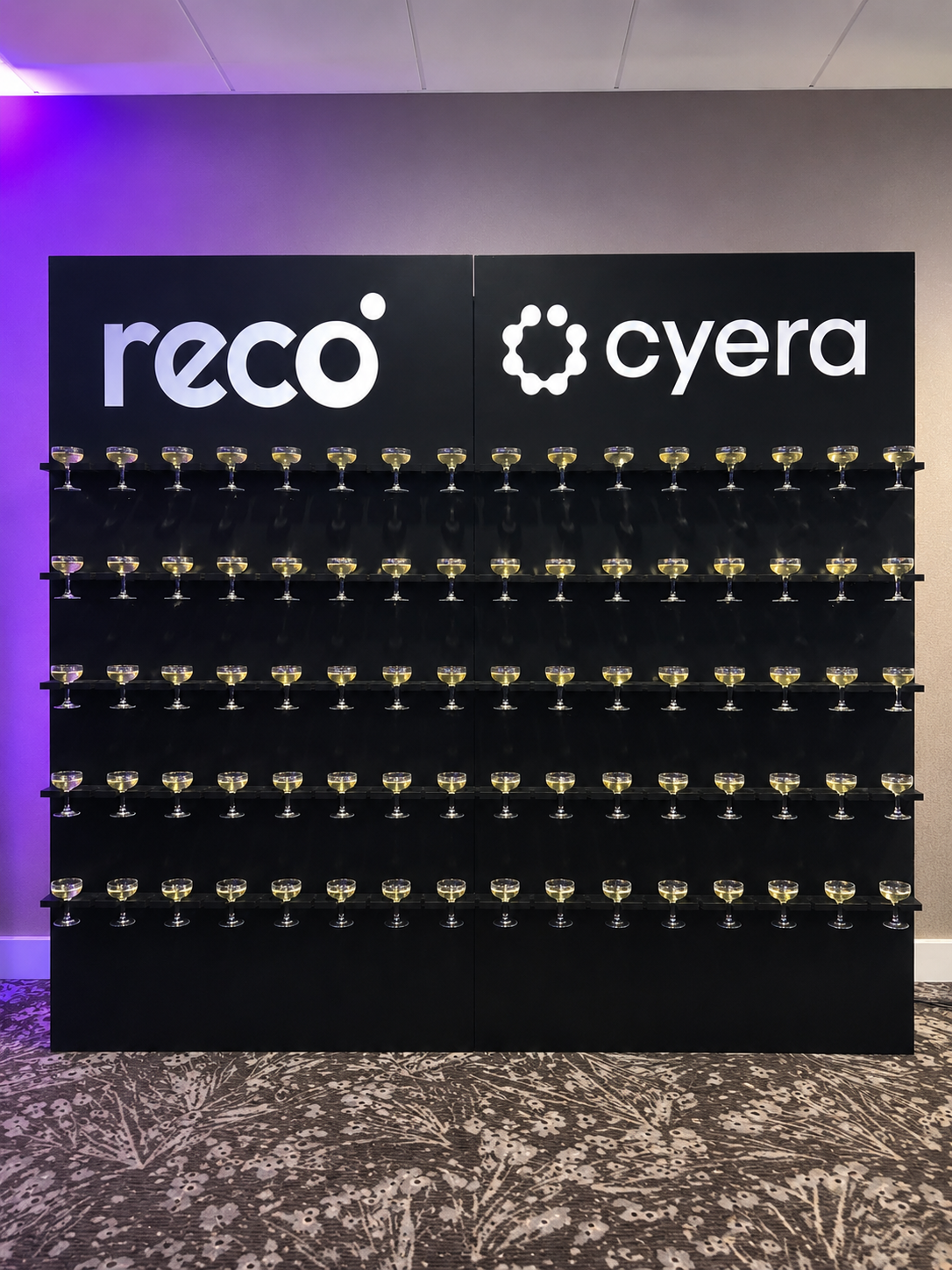Black champagne wall rental Chicago — corporate event setup with custom logo panels and champagne coupes on tiered shelves
