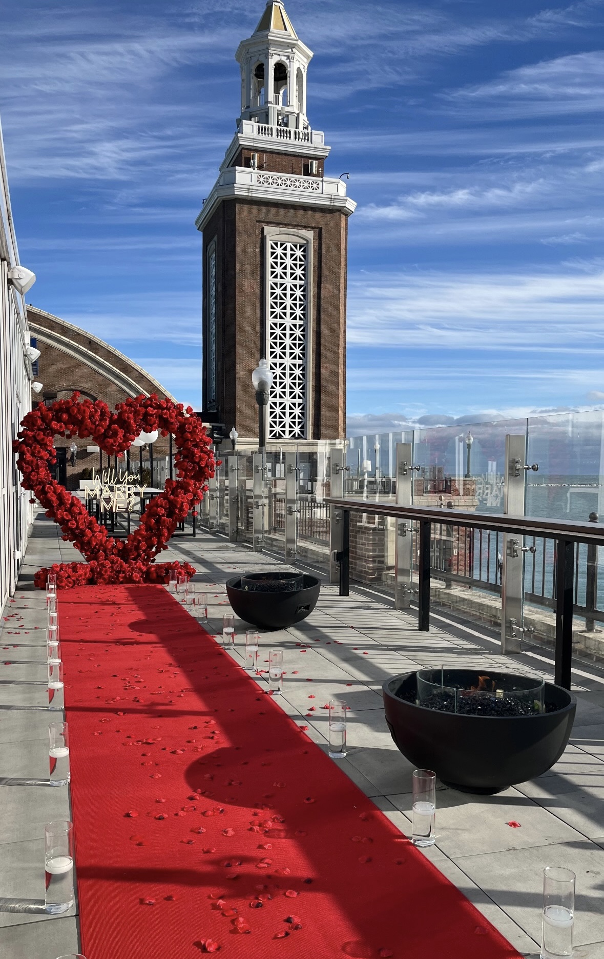 Chicago marriage proposal setup — floral heart arch with neon sign and red rose petal carpet