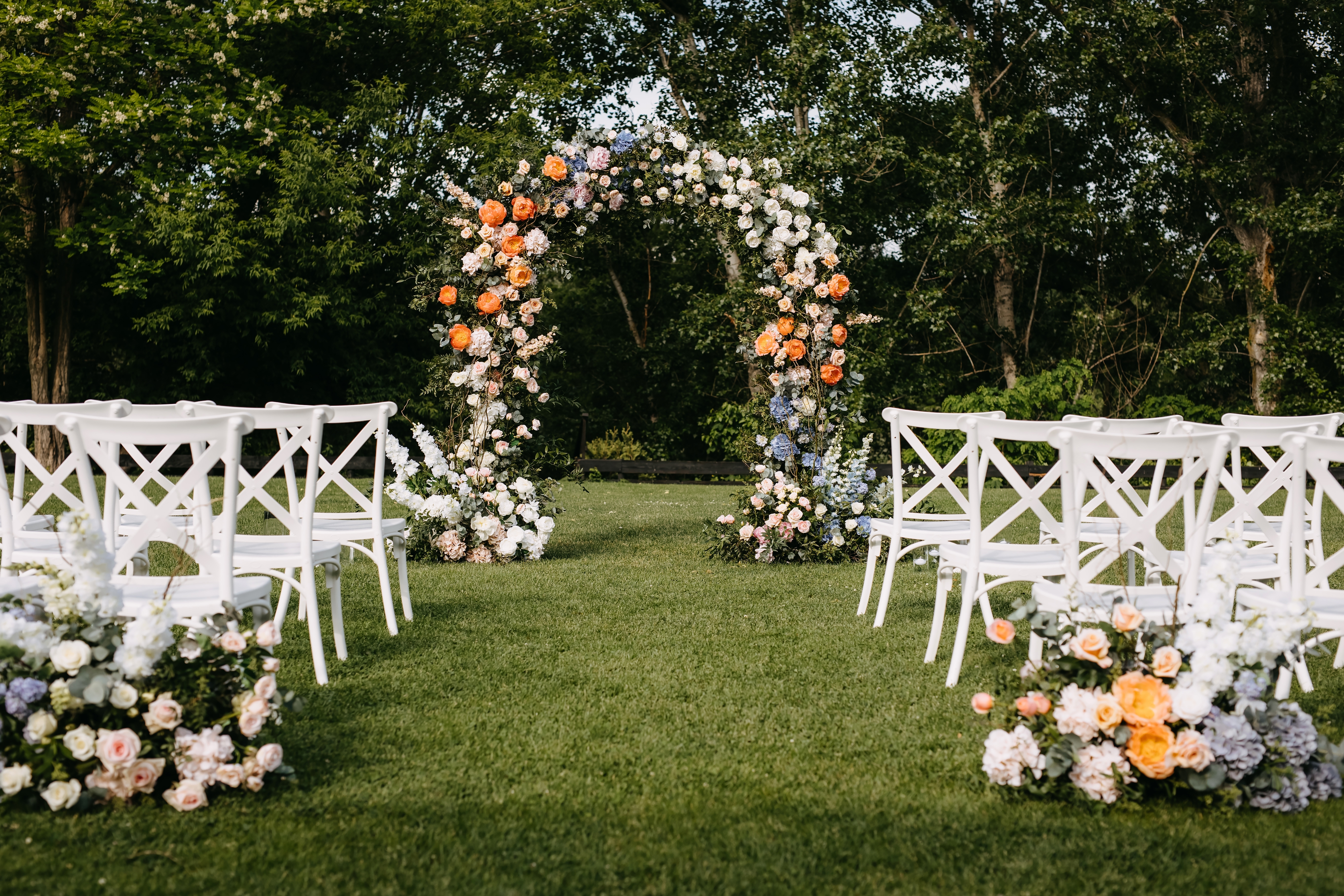 Garden wedding ceremony with colorful flower arch and matching blush peach aisle arrangements — Chicago