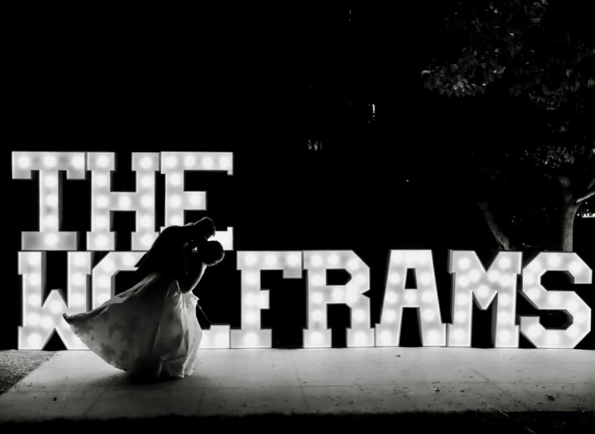 Wedding couple silhouette kissing in front of glowing illuminated marquee letters