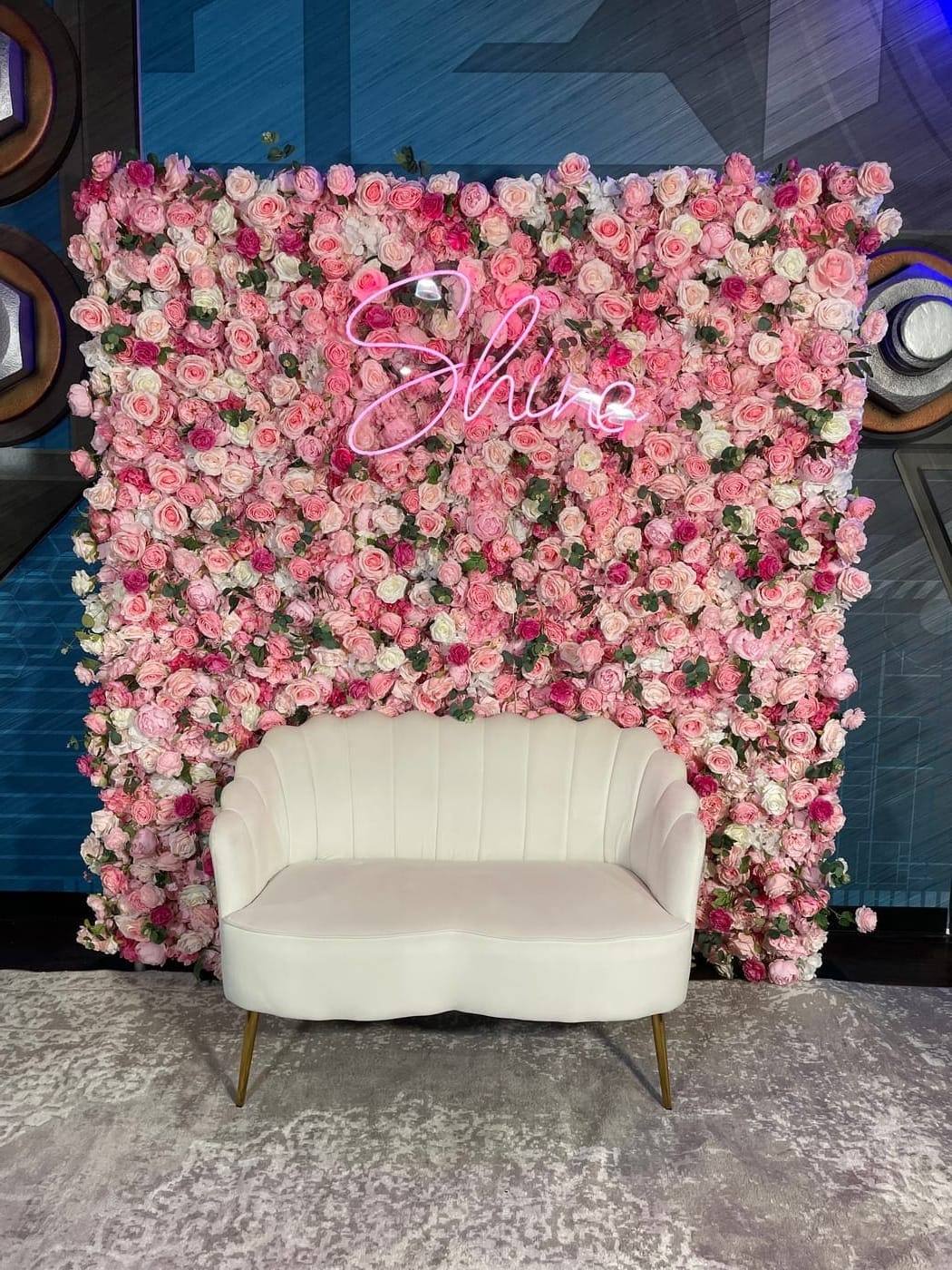 Flower wall backdrop rental in Chicago — pink and cream roses with a white loveseat and Shine neon