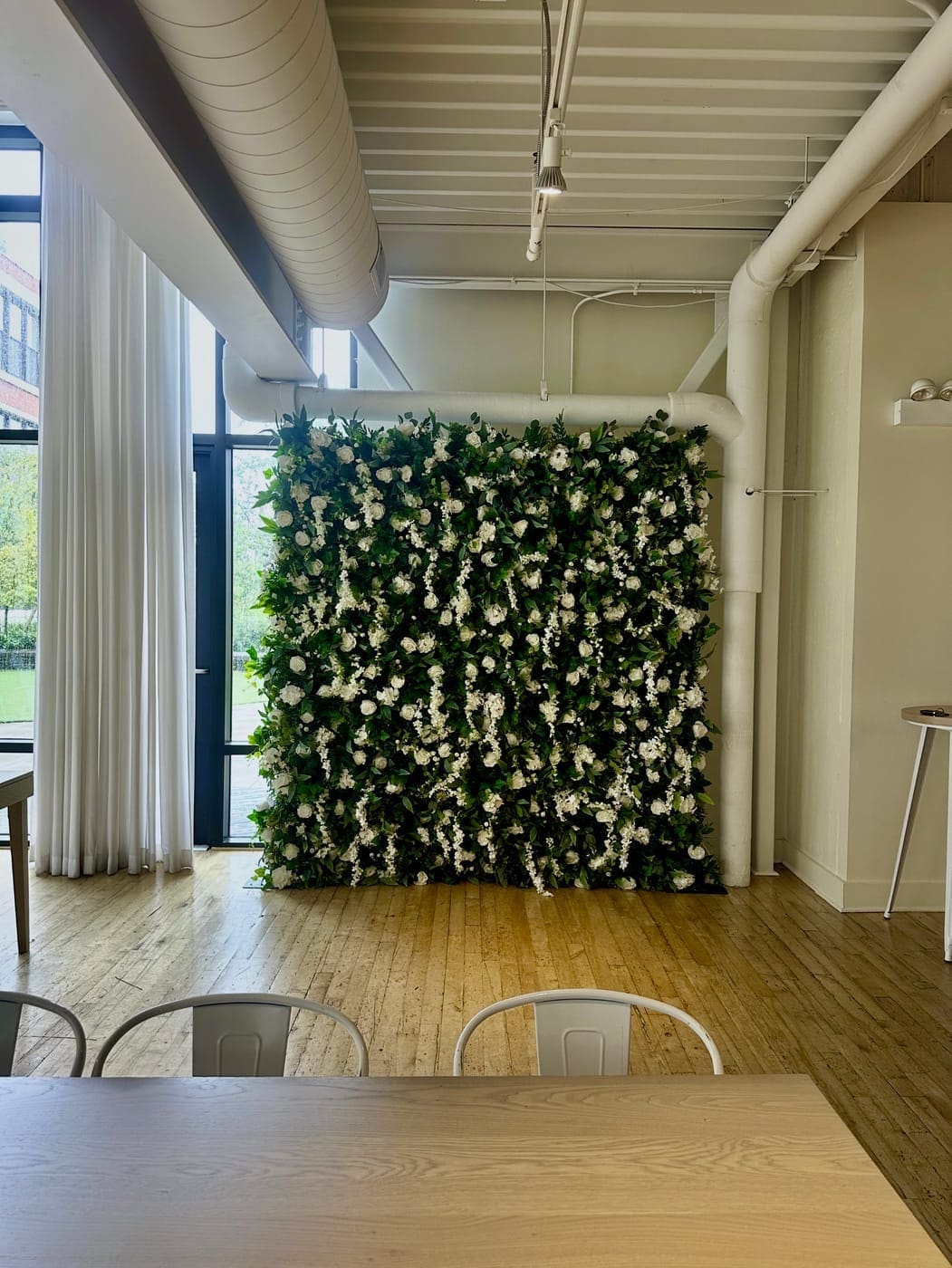 Greenery flower wall rental Chicago IL — lush green wall with white roses at indoor event venue
