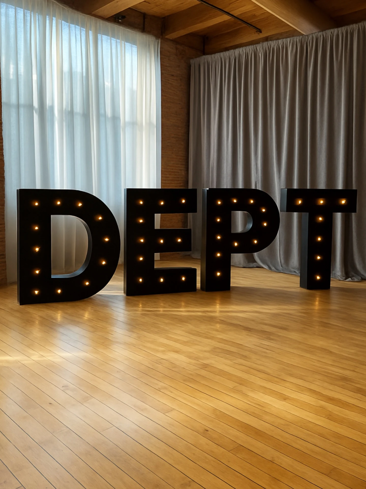 Marquee letter rental in Chicago with custom black marquee letters spelling DEPT with warm bulbs on a wood floor in a loft event space