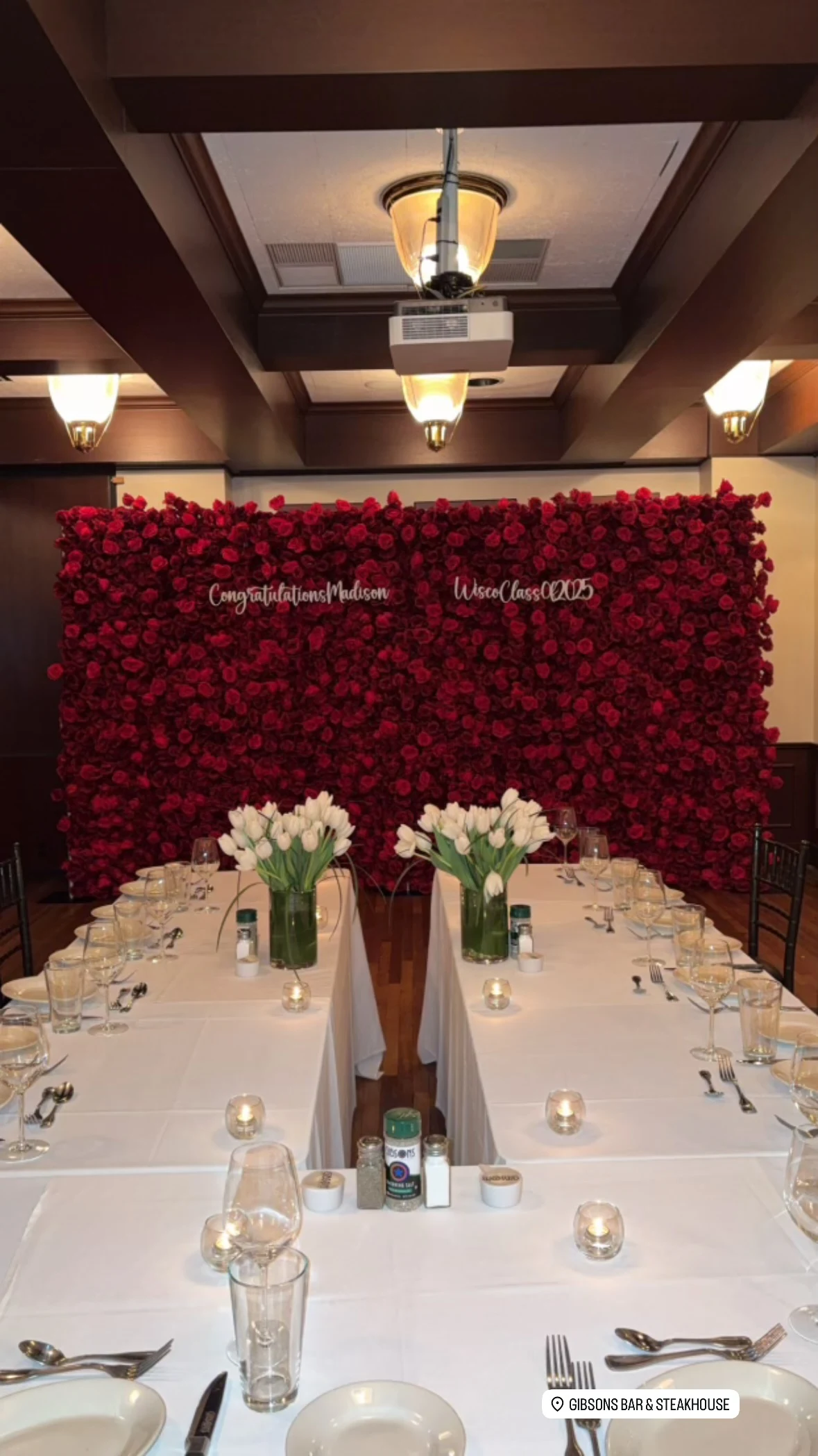 Flower wall rental in Chicago — red rose flower wall with Congratulations Madison script lettering behind a graduation dinner at Gibsons Bar and Steakhouse