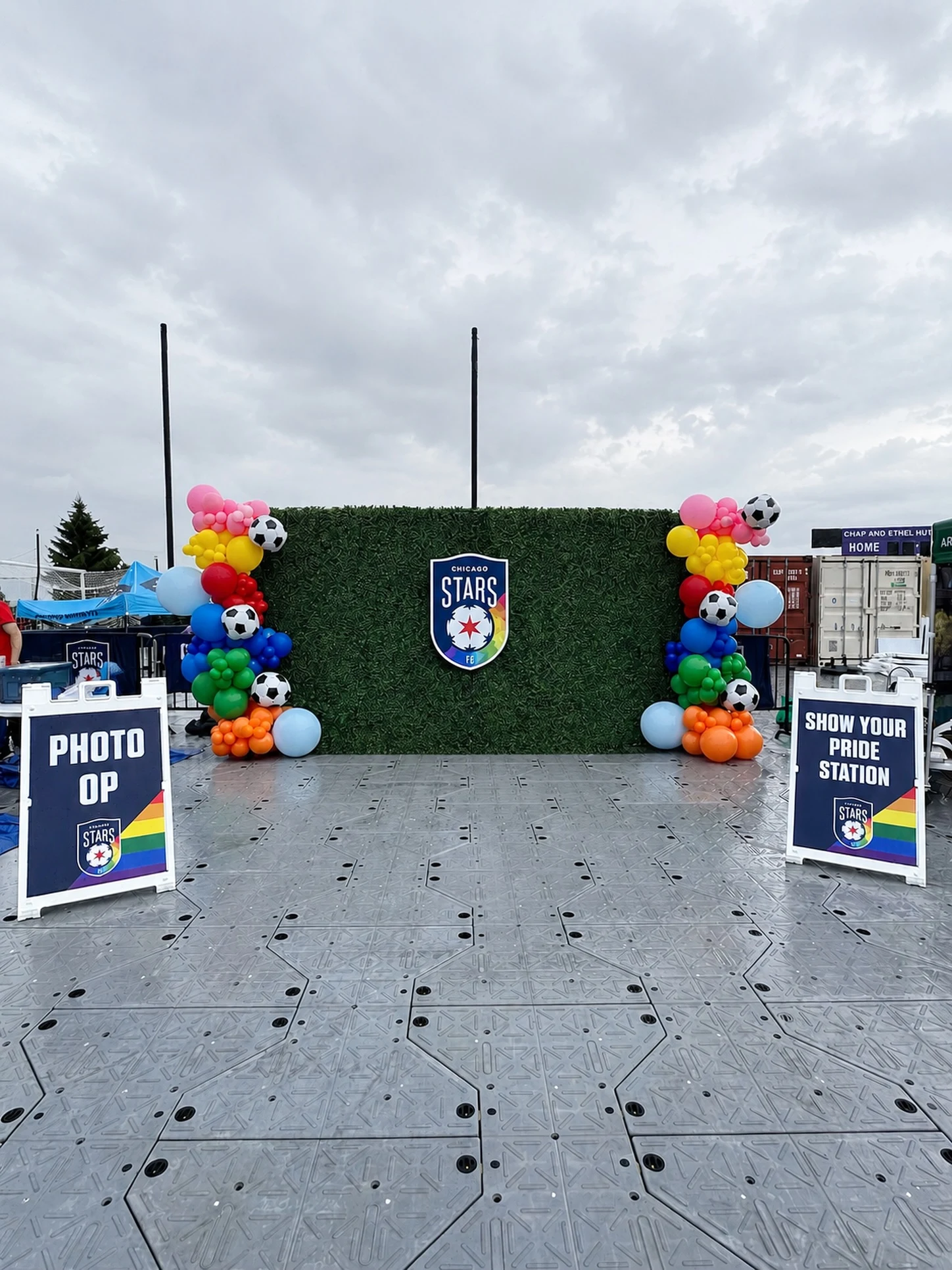 hedge wall backdrop rental in Chicago — green hedge wall with Chicago Stars FC crest flanked by rainbow balloon columns with soccer ball balloons at a Pride match photo op