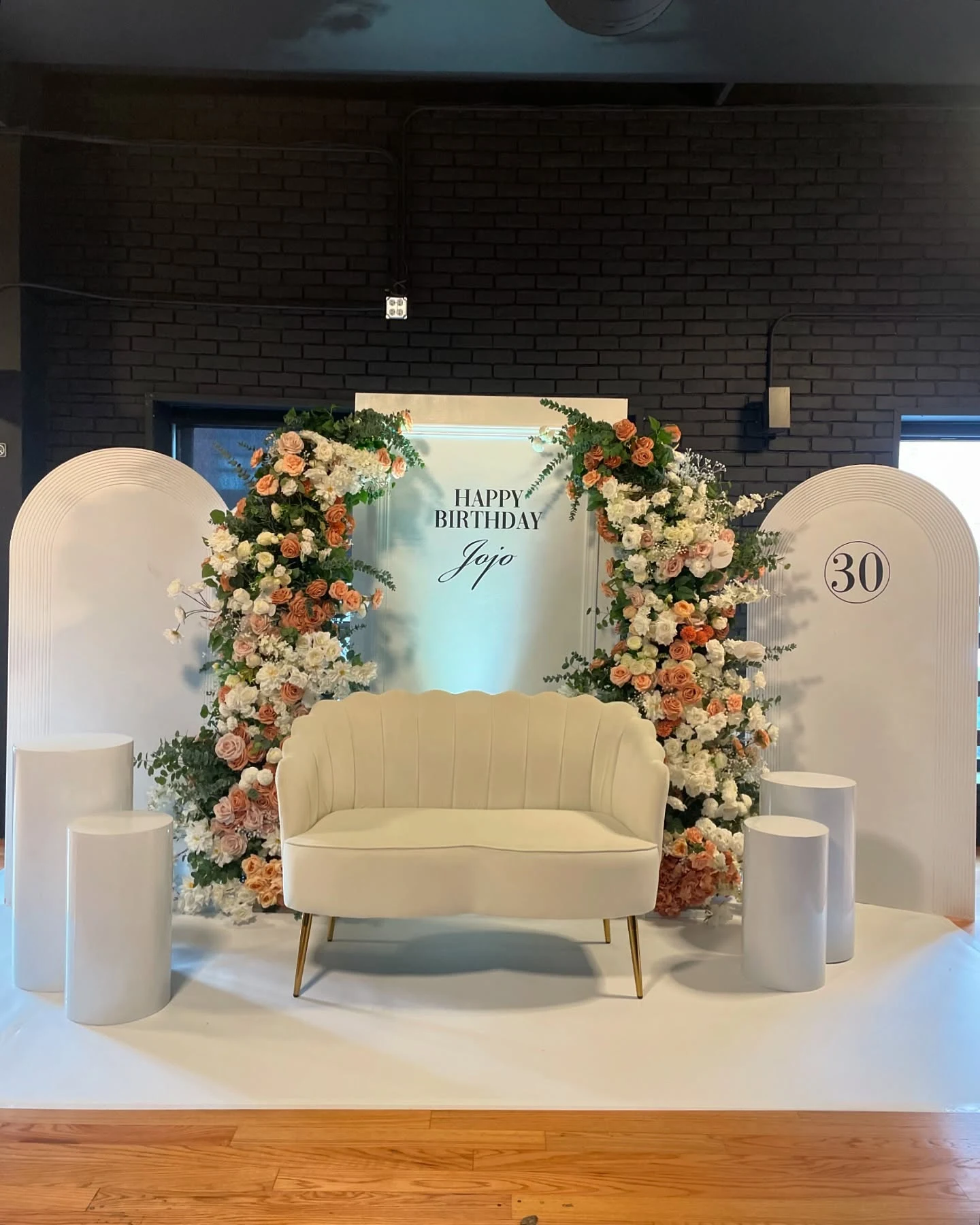 Backdrop rental in Chicago — white Happy Birthday Jojo panel framed by peach and white floral columns, arched side panels with a circled 30, and a cream scalloped loveseat at a 30th birthday