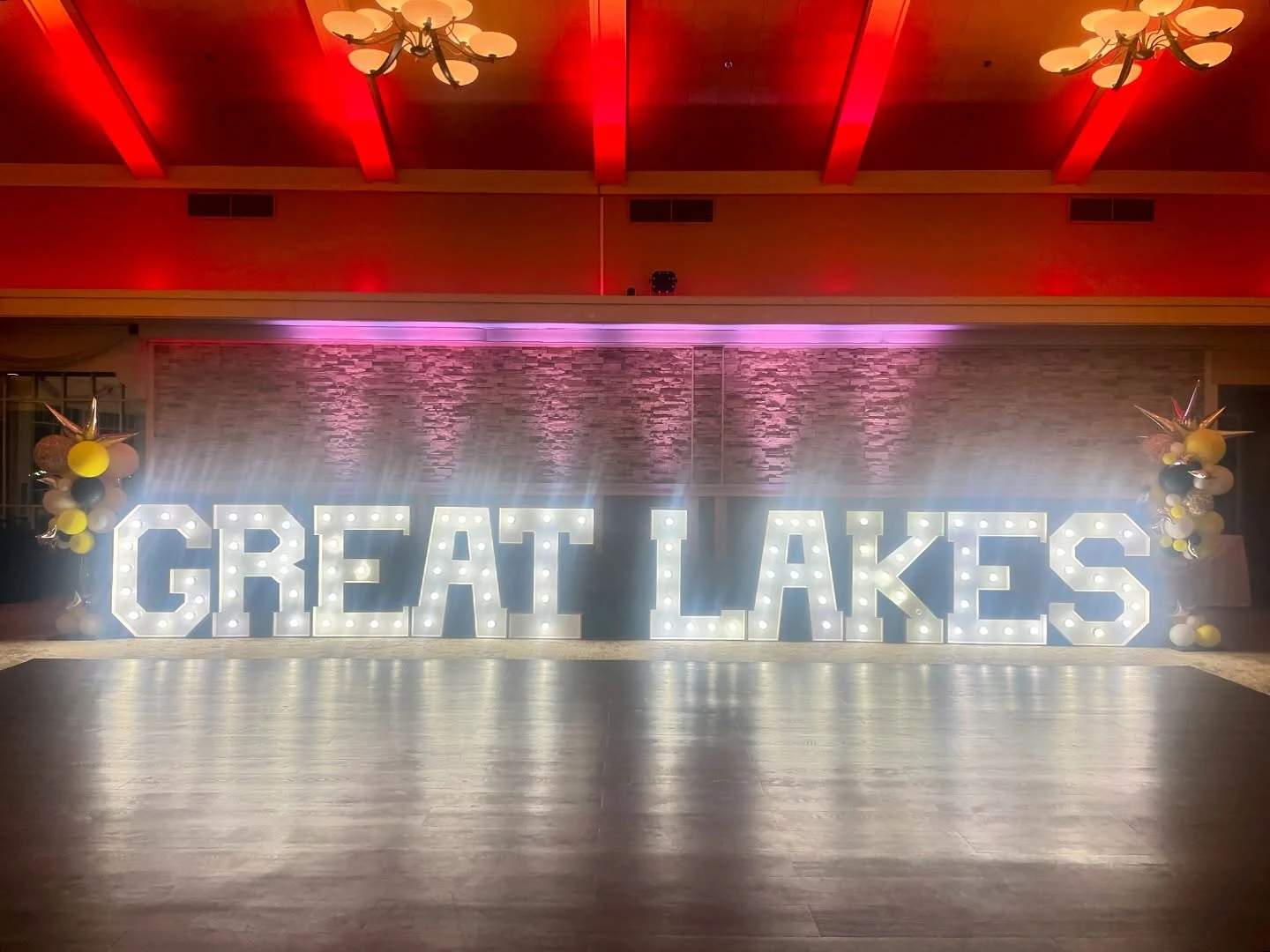 Marquee letter rental in Schaumburg — illuminated GREAT LAKES marquee letters in front of a dance floor at Schaumburg Golf Club, yellow and black balloon clusters at both ends