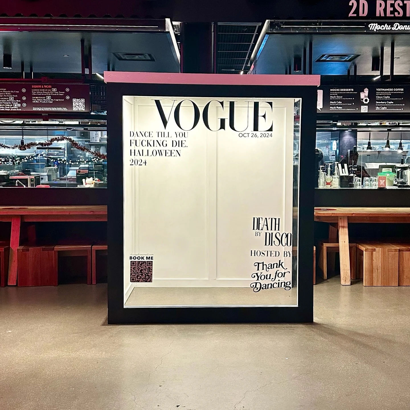 Magazine photo booth rental in Chicago — black-framed magazine cover photo booth with a Halloween 2024 cover standing in a Fulton Market food hall