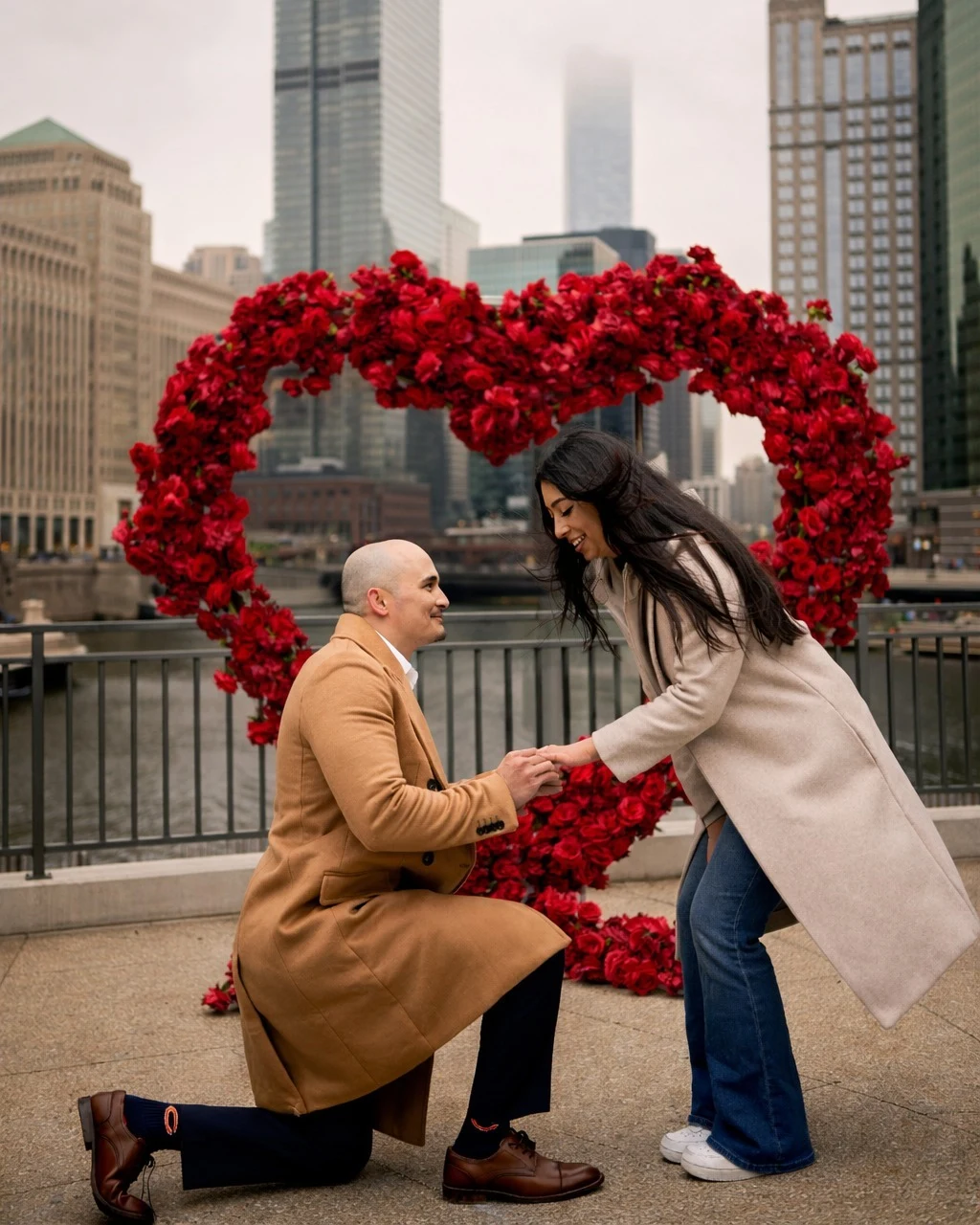Red rose heart arch rental in Chicago on the Riverwalk, with Dylan on one knee proposing to Xena in front of the downtown skyline
