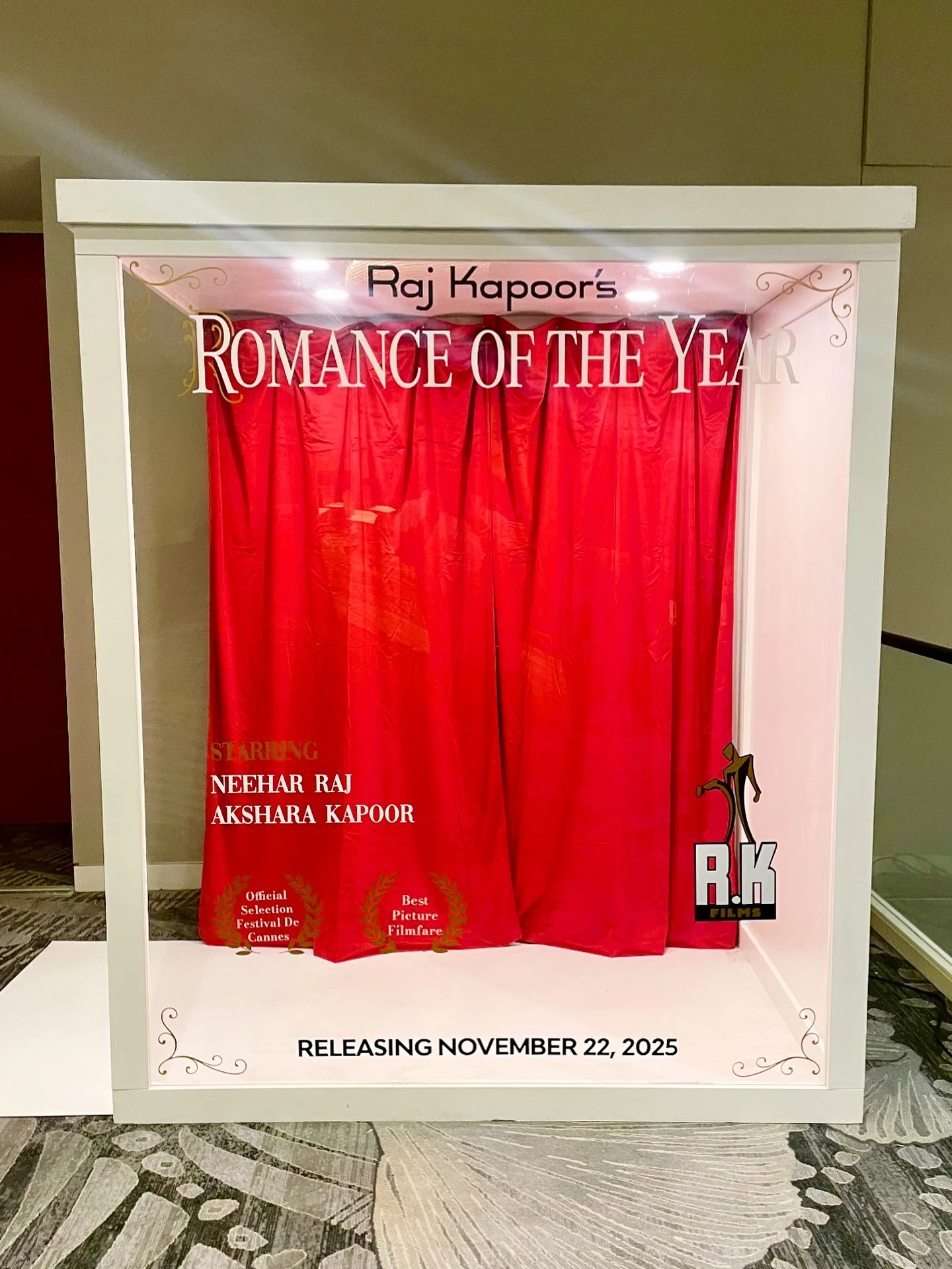 Magazine photo booth rental in Schaumburg with a white movie poster box reading Romance of the Year and a red curtain backdrop at a Night at the Oscars wedding
