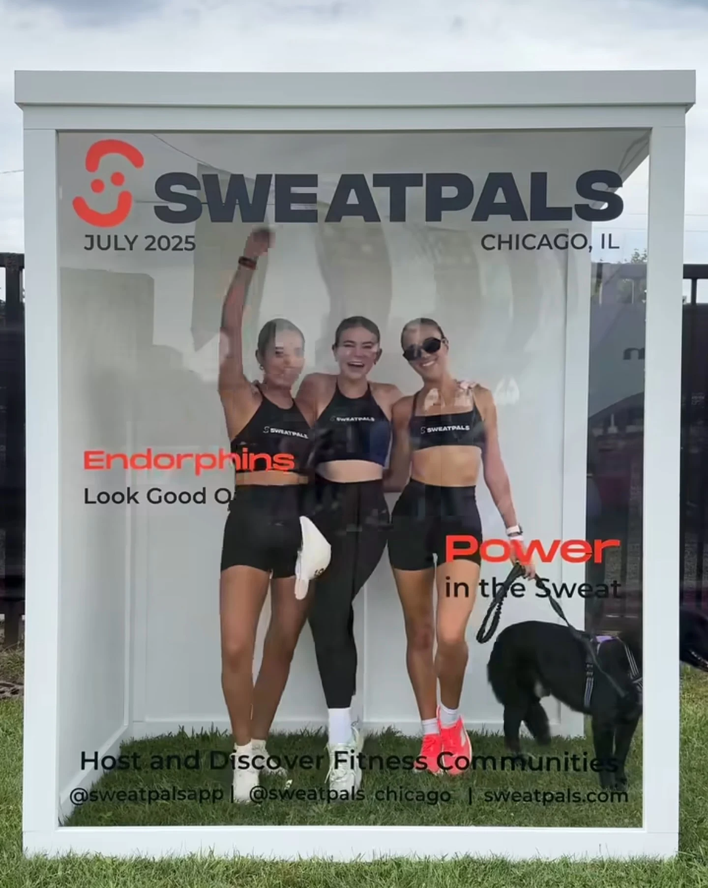 Magazine cover photo booth rental in Chicago — white magazine box re-skinned as a Sweatpals cover, three festival guests in athletic wear posing behind the glass front at an outdoor fitness festival