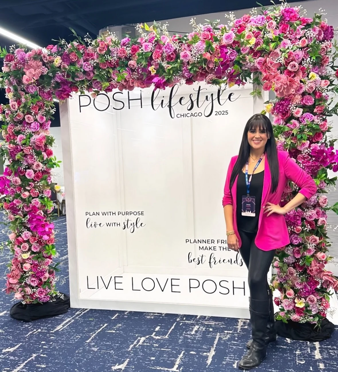 Magazine cover photo booth in Chicago seen from outside with a full pink rose floral frame around the POSH Lifestyle cover and a conference attendee in a pink blazer posing beside it