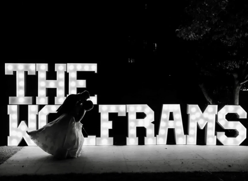 Light-up marquee letter rental in Elgin spelling THE WOLFRAMS at night with the wedding couple dancing in front
