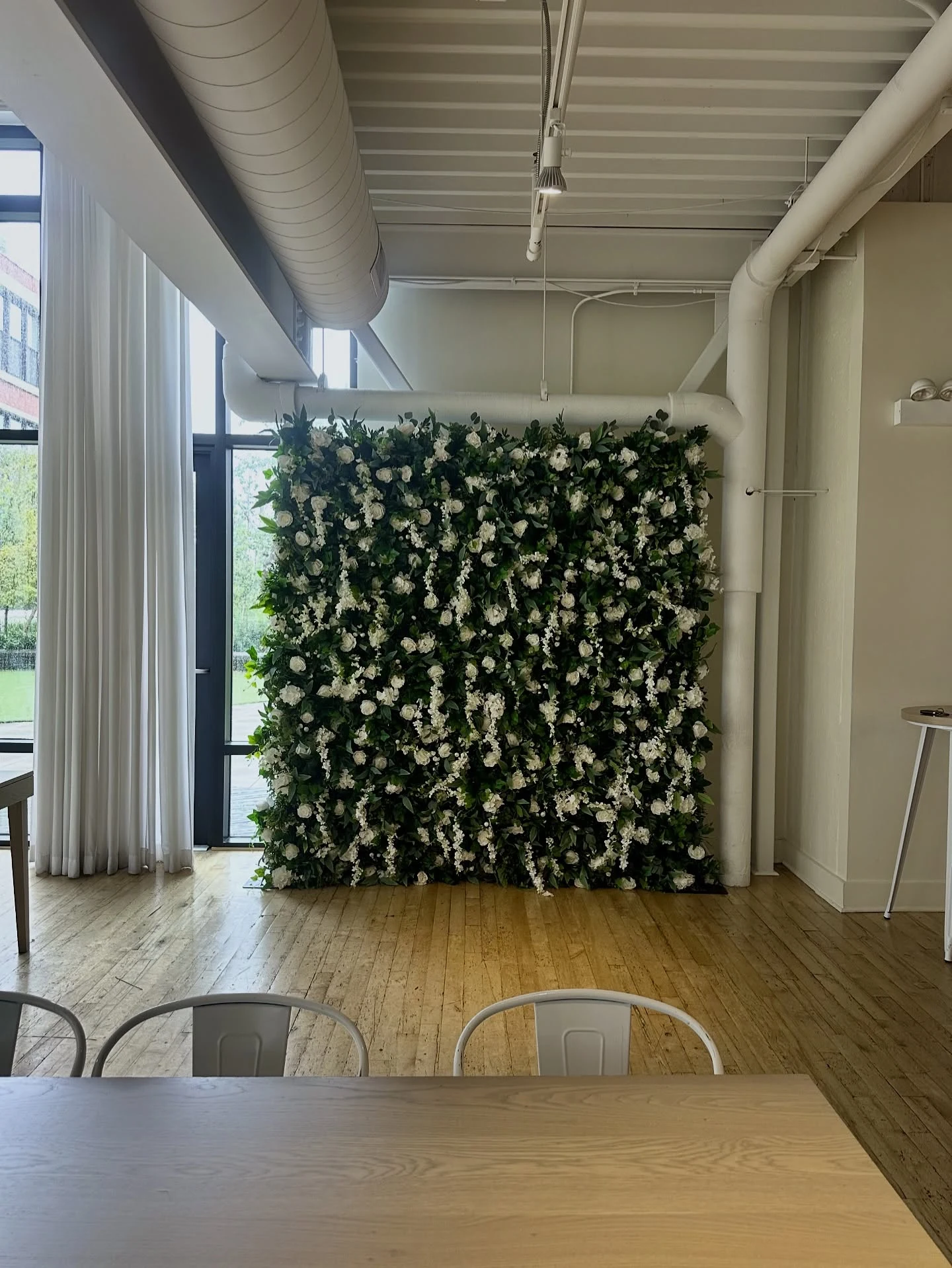 Flower wall rental in Chicago — 4D wall of lush greenery, white roses and hanging white florals in a bright loft-style room with wood floors