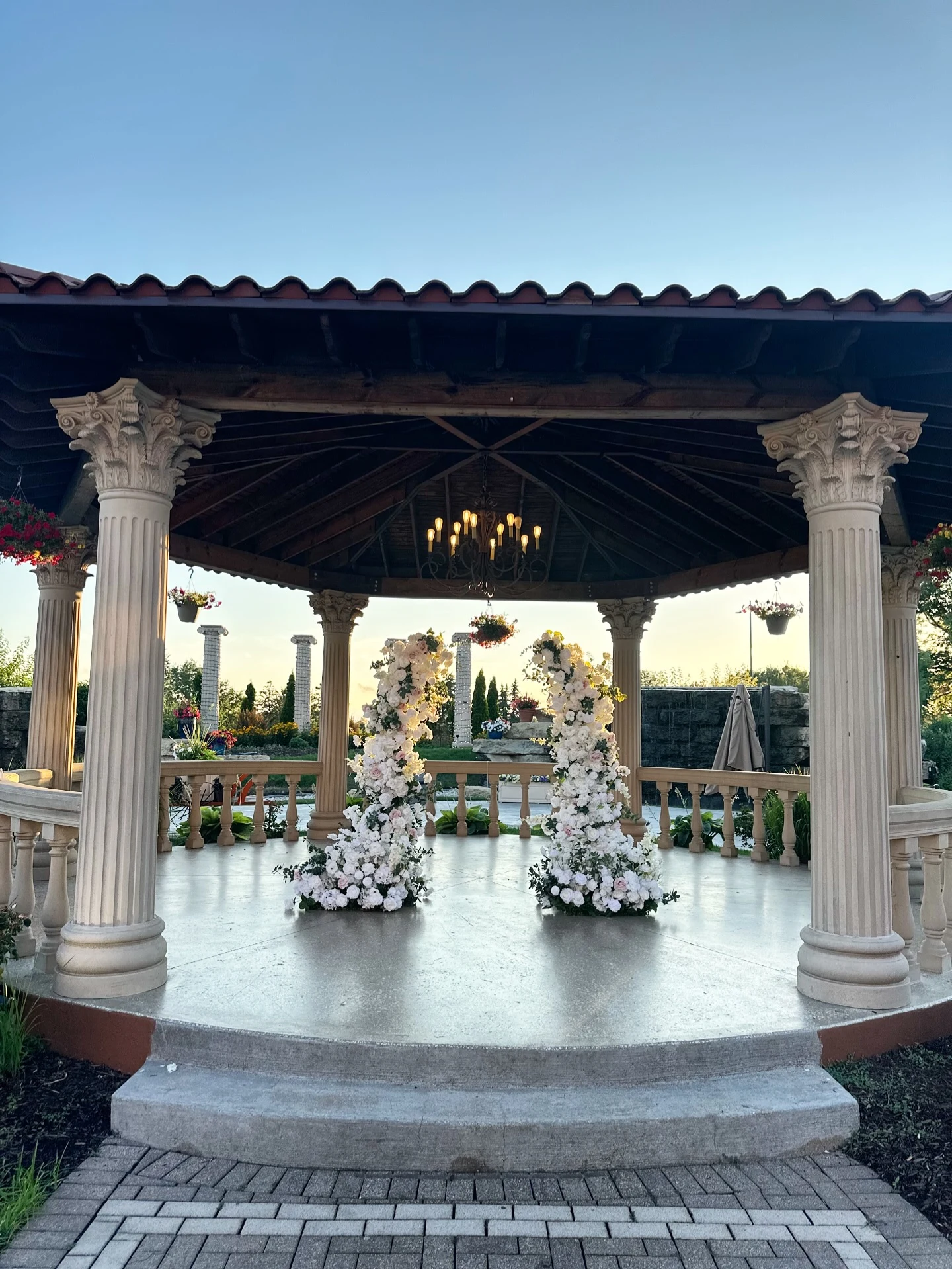 Floral pillar rental in Oak Brook — pair of tall ivory floral pillars framing a ceremony inside a columned garden gazebo at golden hour