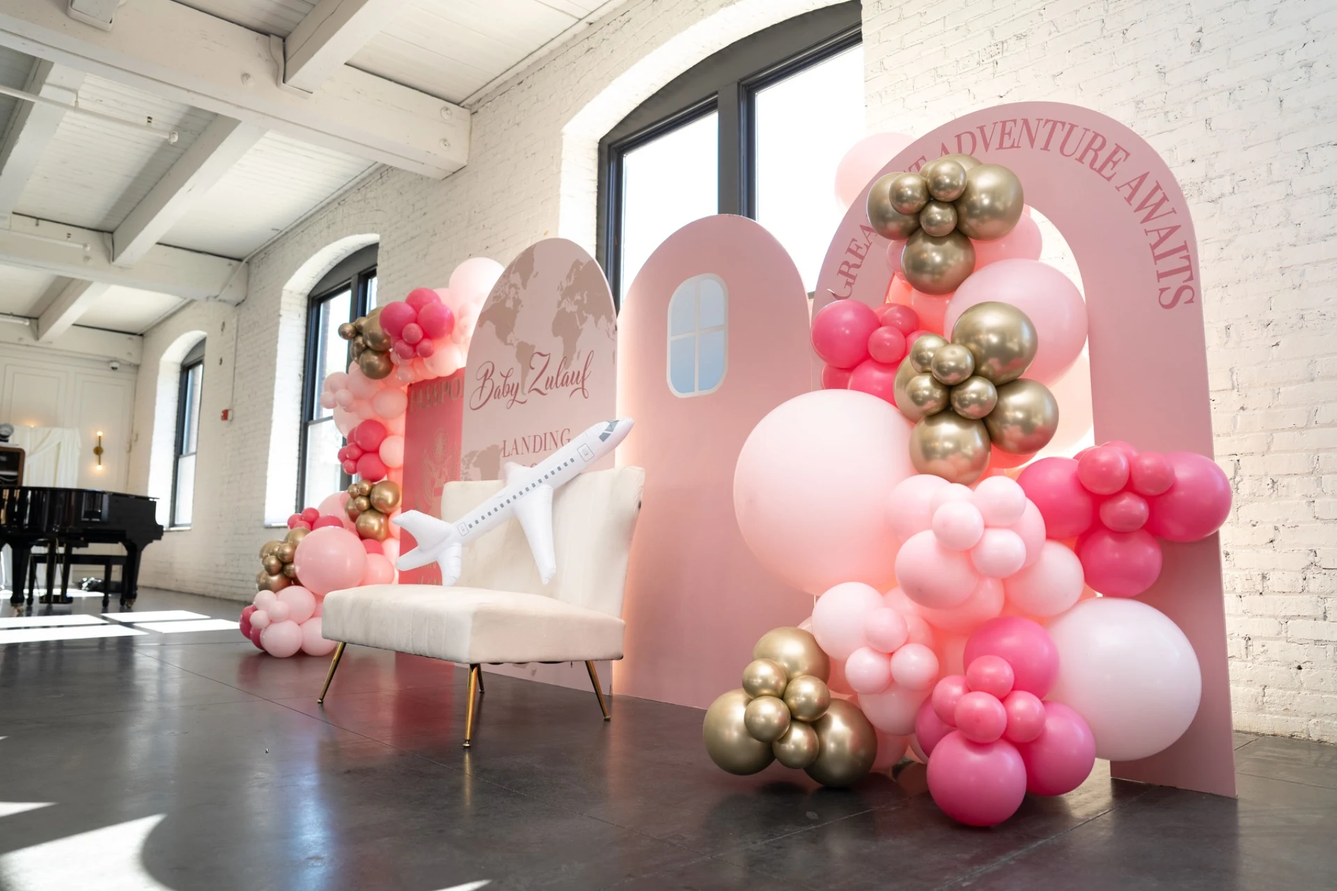 balloon garland rental in Aurora — pink and gold balloon garland on an arched backdrop panel beside a grand piano
