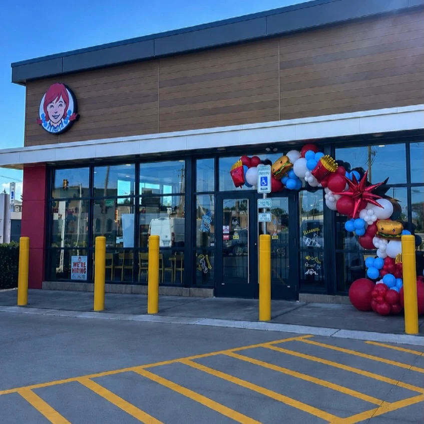 grand opening balloon arch rental in Chicago — red white and blue balloon garland with burger and fries foil balloons over the entrance of a new Wendys restaurant