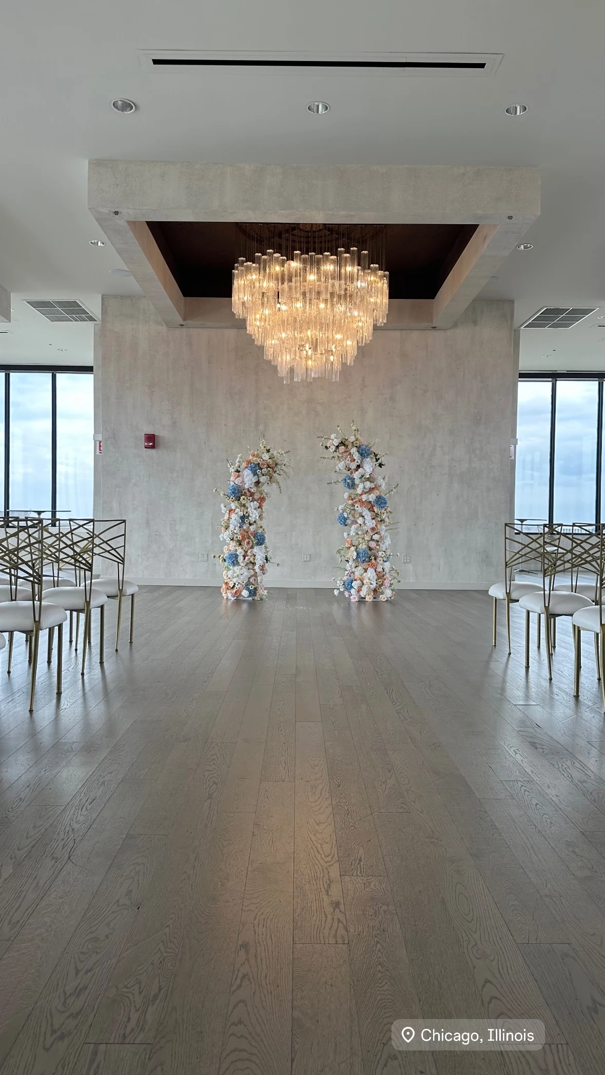 Floral pillar rental in Chicago — two floral pillars in white, blush, and dusty blue framing a ceremony aisle beneath a crystal chandelier