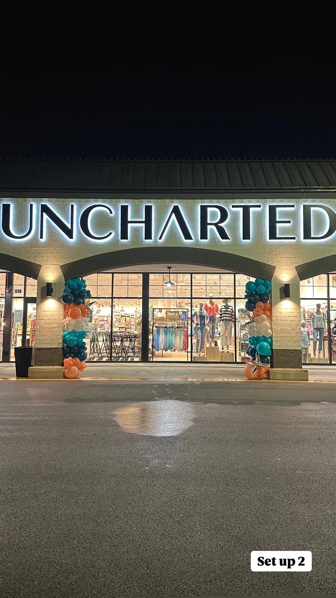 Balloon column rental in Chicago — teal, navy, coral, and white balloon columns flanking the entrance of an Uncharted store at night